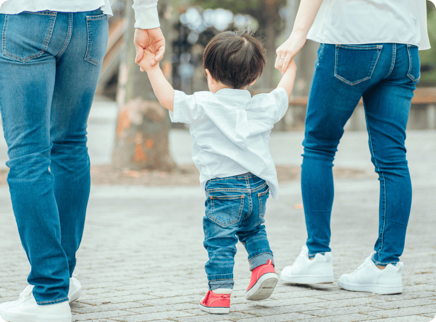 両親と手を繋いで歩く男の子の写真